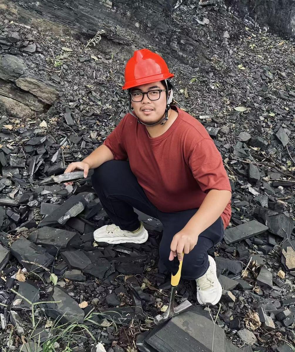 Li Zeyu examining a rock outcrop in the field.