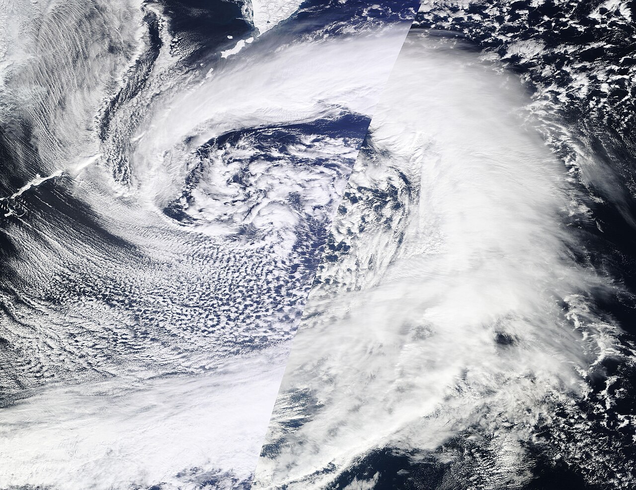 A broad spiral of white clouds over the Pacific northeast of Japan.