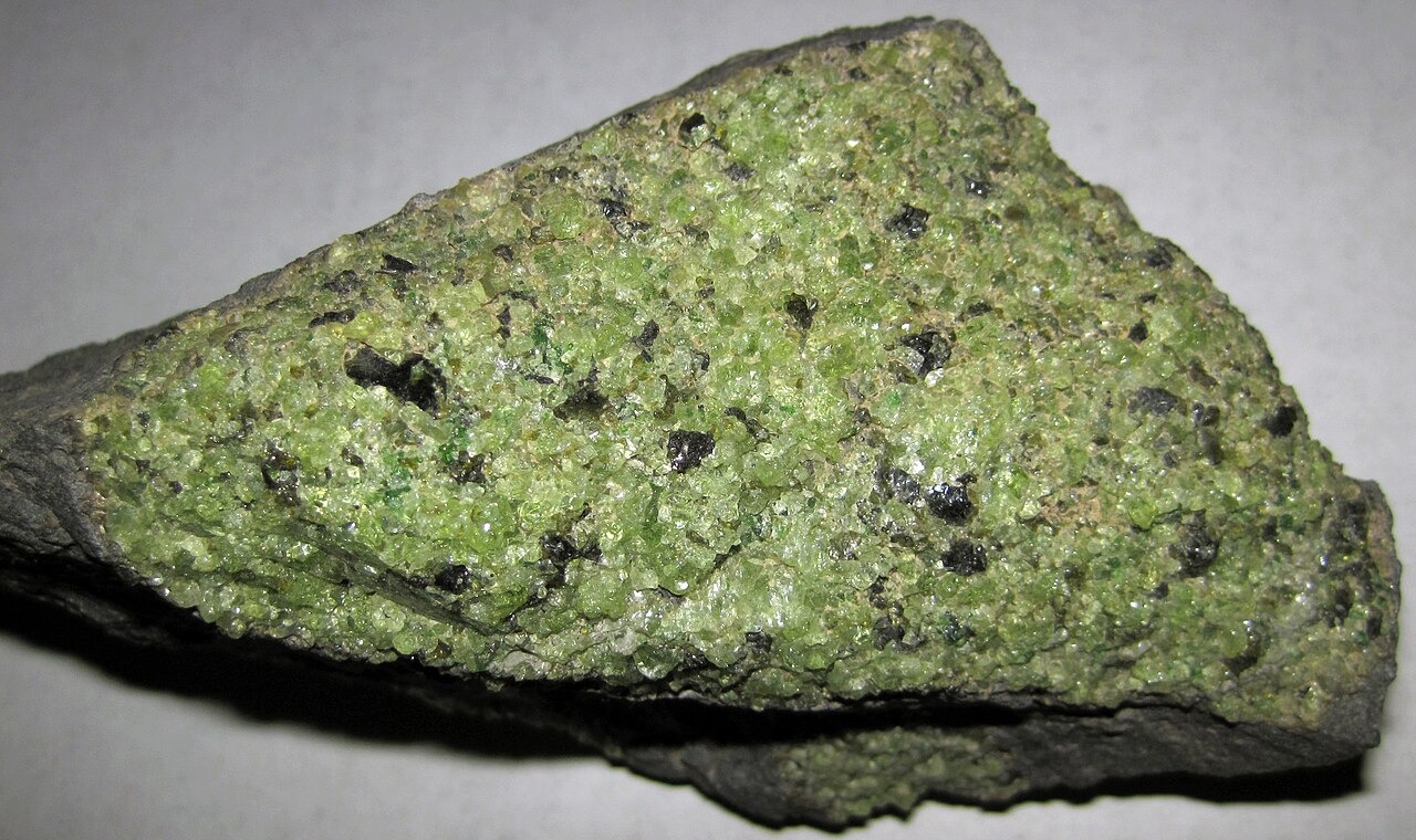Green crystalline mantle peridotite enclosed by darker volcanic host rock at Peridot Mesa, Arizona.