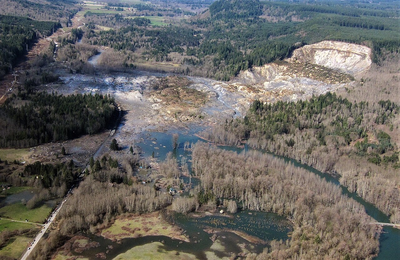 An aerial view of the Oso landslide's bare source scar, debris path and deposits across the valley.