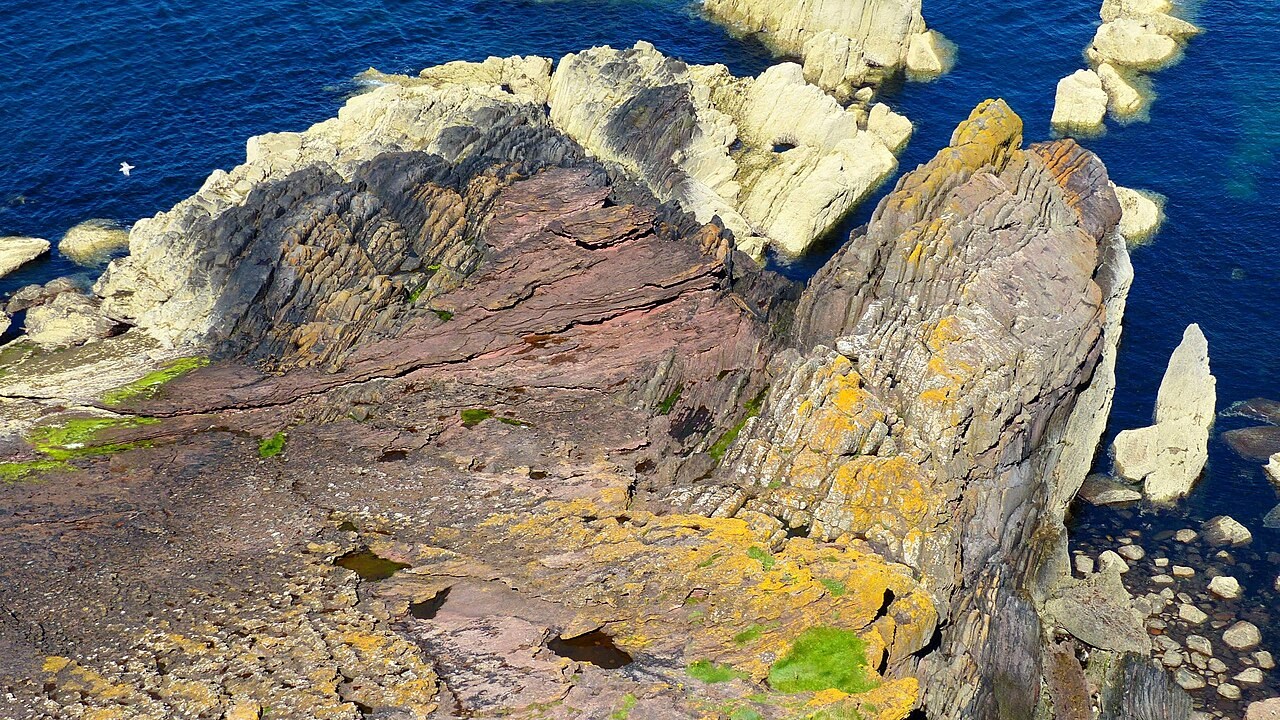 Younger gently dipping red sandstone overlies steep grey beds at Siccar Point, Scotland.